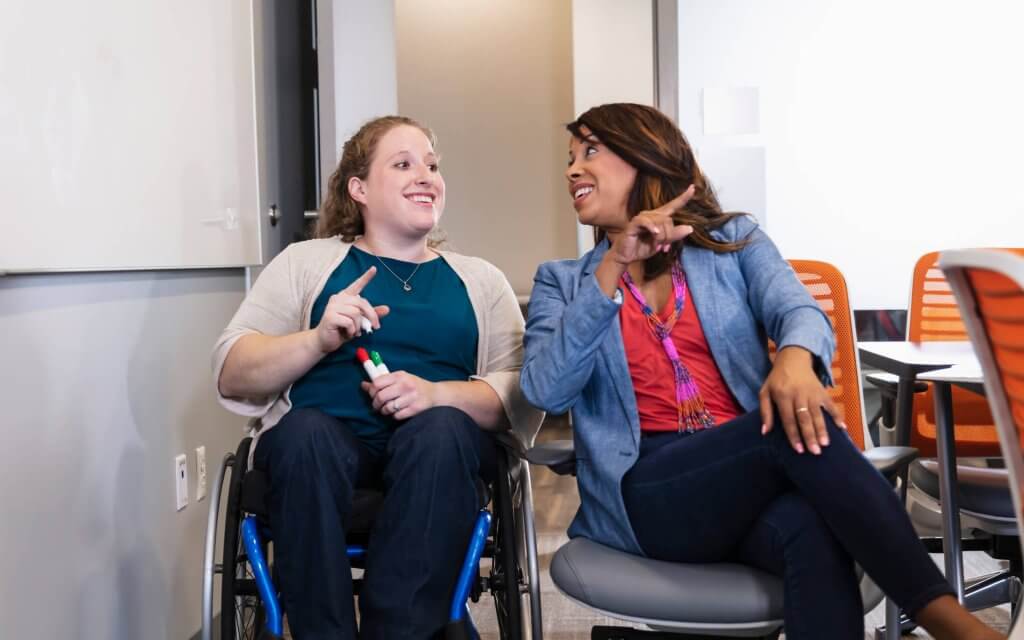 Two women talking, one of whom is in a wheelchair